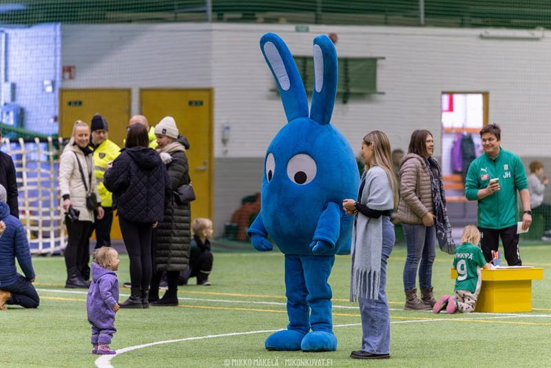 Kuvateksti: Jalkapallon esikuvien lisäksi pientä väkeä ilahdutti Osmo-maskotin kohtaaminen. Kuvaaja: Mikko Mäkelä